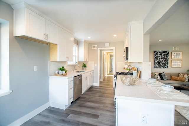 kitchen with tasteful backsplash, white cabinets, a peninsula, stainless steel appliances, and a sink