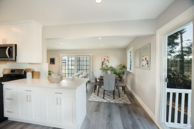 kitchen with baseboards, white cabinets, dark wood finished floors, appliances with stainless steel finishes, and light countertops