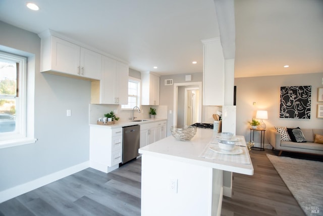 kitchen featuring dishwasher, light countertops, a sink, and white cabinetry