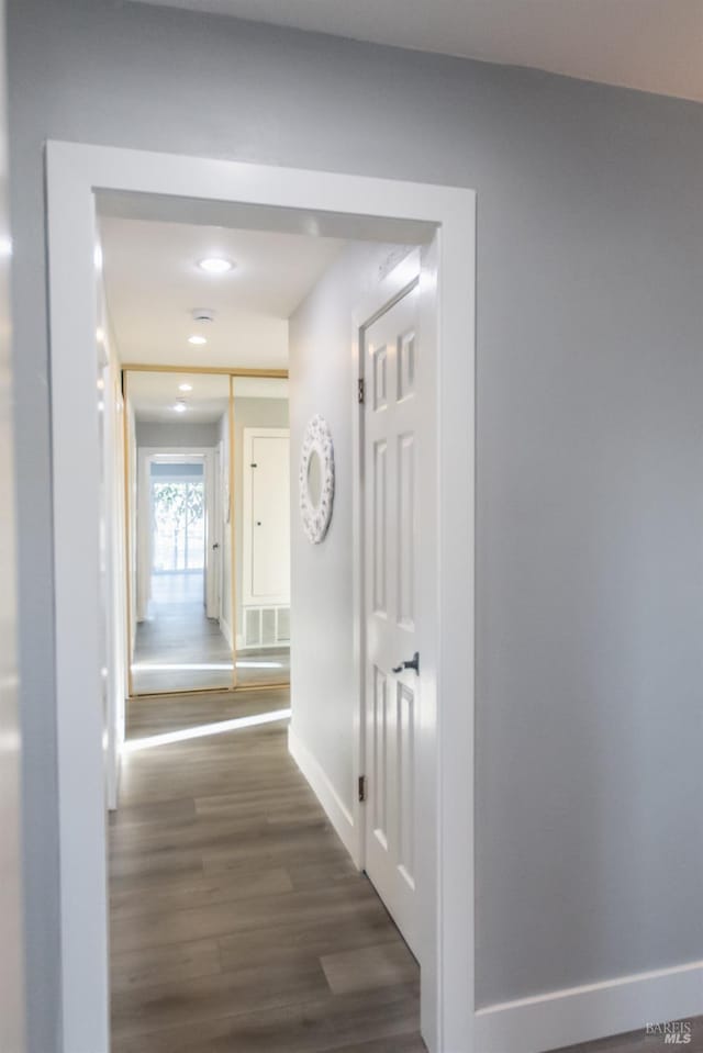 hallway featuring baseboards, visible vents, dark wood-type flooring, and recessed lighting