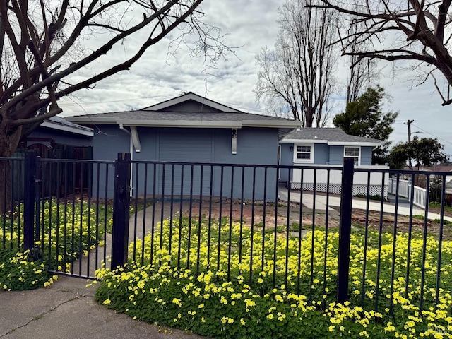 view of front of property with a fenced front yard, a gate, roof with shingles, and a front lawn