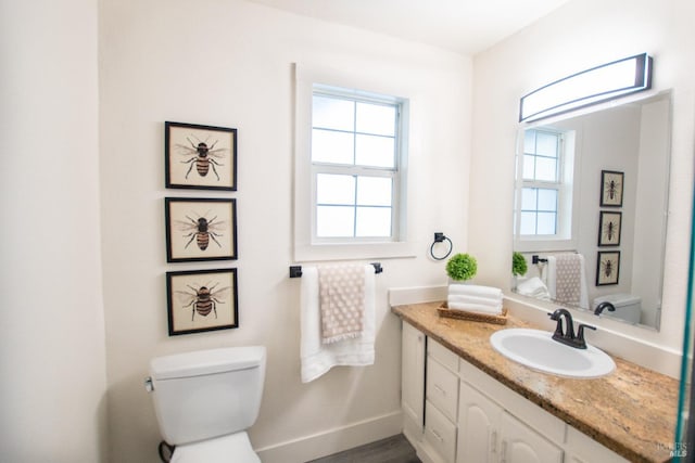 bathroom with toilet, baseboards, and vanity