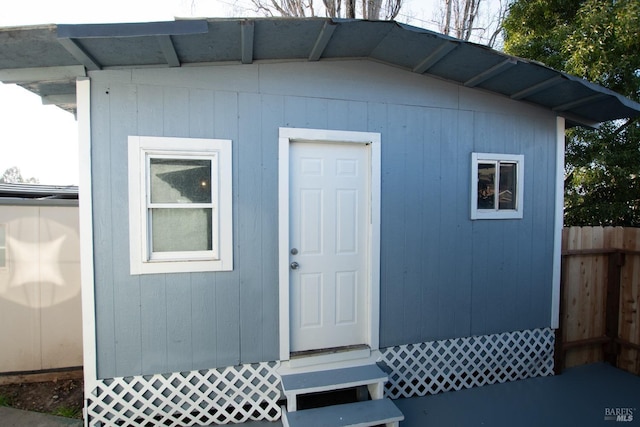 view of outdoor structure featuring entry steps, fence, and an outbuilding