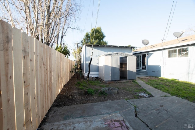 view of yard featuring a fenced backyard, a storage unit, a patio, and an outdoor structure