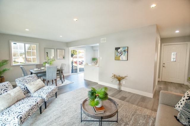 living room featuring recessed lighting, wood finished floors, visible vents, and baseboards