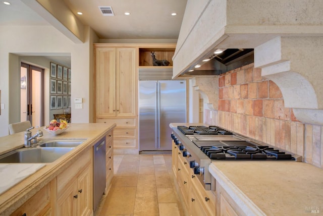 kitchen featuring backsplash, premium range hood, stainless steel appliances, sink, and light brown cabinets