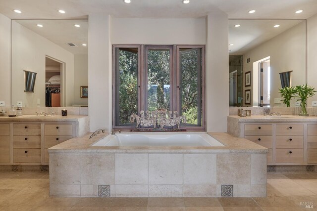 bathroom featuring vanity and a relaxing tiled tub