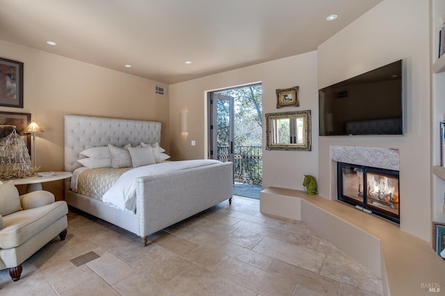 bedroom with a multi sided fireplace and access to exterior