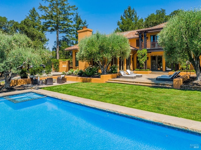 back of house with a patio area, a balcony, a yard, and a swimming pool with hot tub