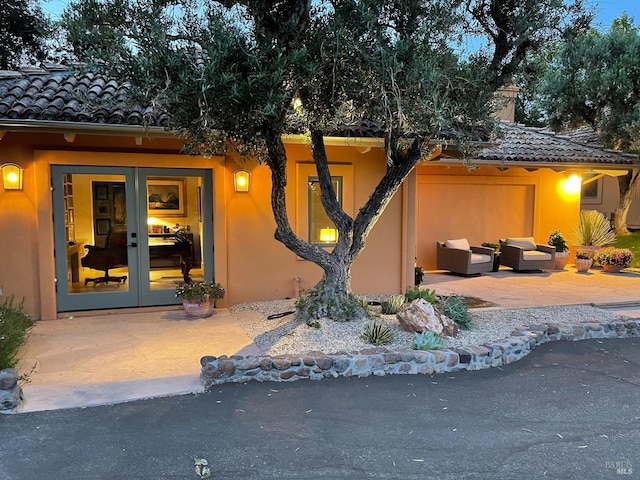 view of exterior entry featuring french doors, a patio, and an outdoor living space