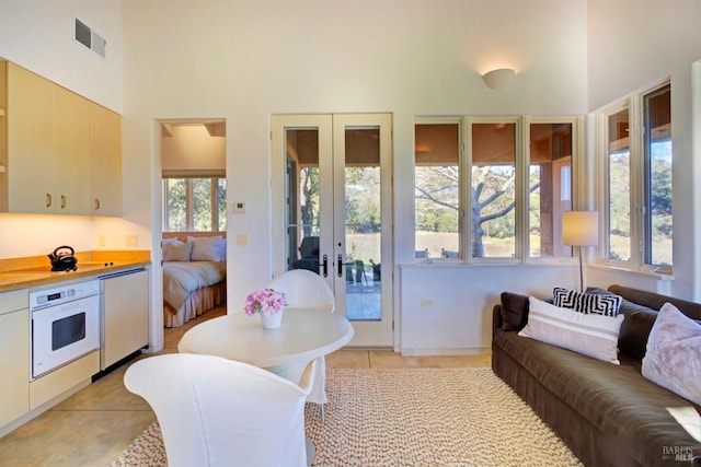 tiled living room with plenty of natural light, a high ceiling, and french doors