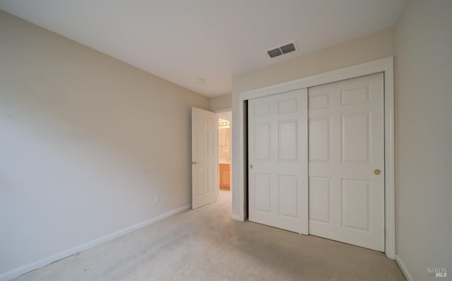 unfurnished bedroom featuring light carpet and a closet