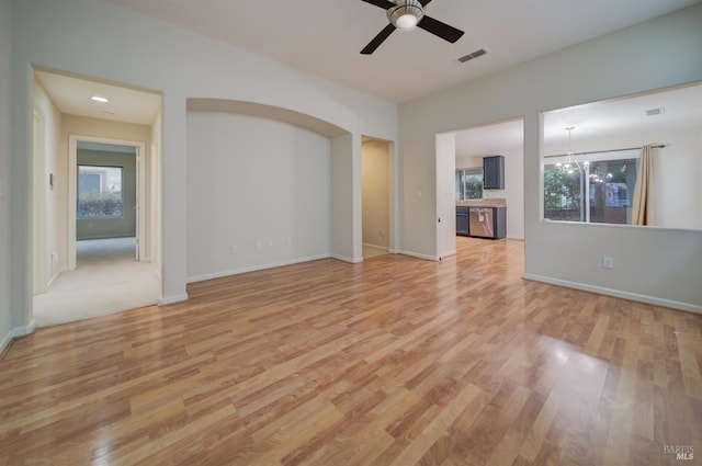 unfurnished living room with ceiling fan with notable chandelier and light wood-type flooring