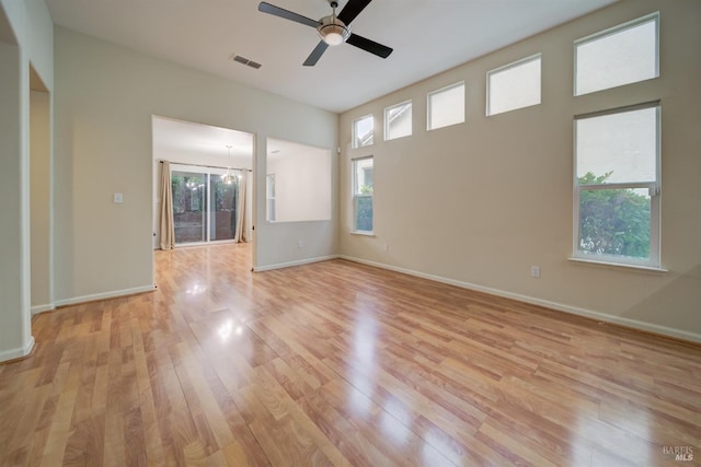 unfurnished room with ceiling fan with notable chandelier and light hardwood / wood-style floors