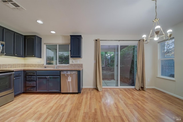 kitchen featuring hanging light fixtures, appliances with stainless steel finishes, a notable chandelier, and light hardwood / wood-style floors