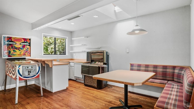 kitchen featuring light hardwood / wood-style flooring, kitchen peninsula, breakfast area, decorative light fixtures, and white cabinets