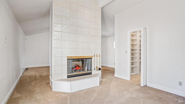 unfurnished living room featuring light colored carpet and a tiled fireplace