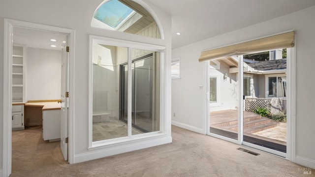 doorway to outside featuring light carpet and vaulted ceiling with skylight