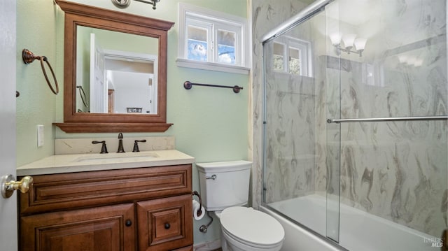 full bathroom with combined bath / shower with glass door, vanity, and toilet