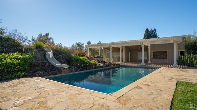 view of swimming pool featuring ceiling fan, a pergola, a patio, and a water slide