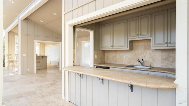 kitchen with a wealth of natural light, wood walls, sink, and vaulted ceiling