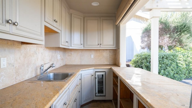 kitchen with light stone countertops, tasteful backsplash, beverage cooler, and sink