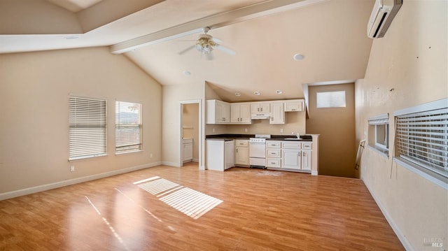 kitchen with stove, light hardwood / wood-style flooring, a wall mounted AC, beamed ceiling, and white cabinetry