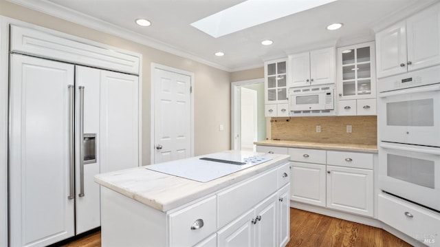 kitchen with a skylight, white cabinetry, built in appliances, and a kitchen island