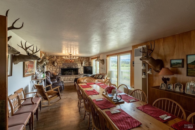 dining space with a fireplace, hardwood / wood-style floors, a textured ceiling, and wood walls