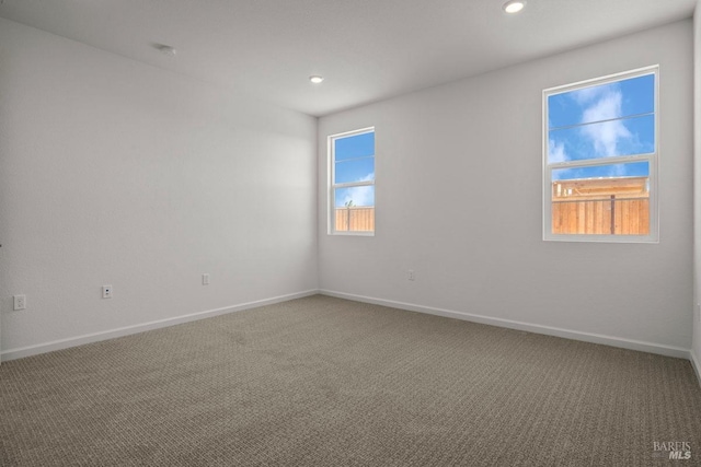 empty room with a wealth of natural light and carpet floors