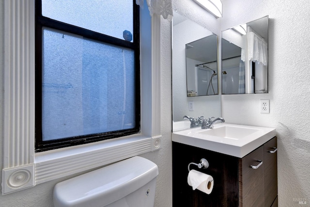 bathroom featuring walk in shower, vanity, and toilet