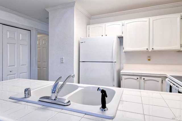 kitchen with tile countertops, white fridge, white cabinets, and crown molding