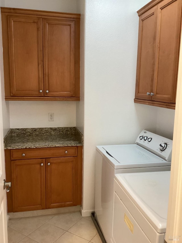 clothes washing area with cabinets, light tile patterned floors, and washing machine and clothes dryer