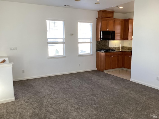 kitchen featuring decorative backsplash, gas stovetop, and light colored carpet