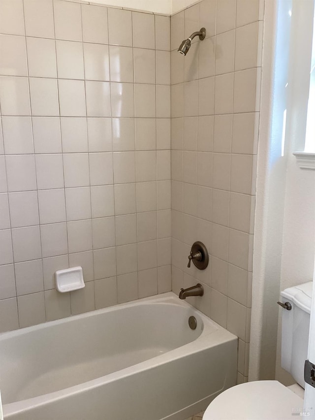 bathroom featuring tiled shower / bath and toilet