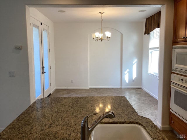 kitchen featuring hanging light fixtures, an inviting chandelier, sink, white appliances, and light tile patterned floors