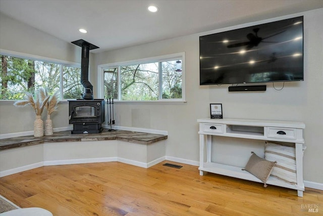 interior space with a wood stove and hardwood / wood-style flooring