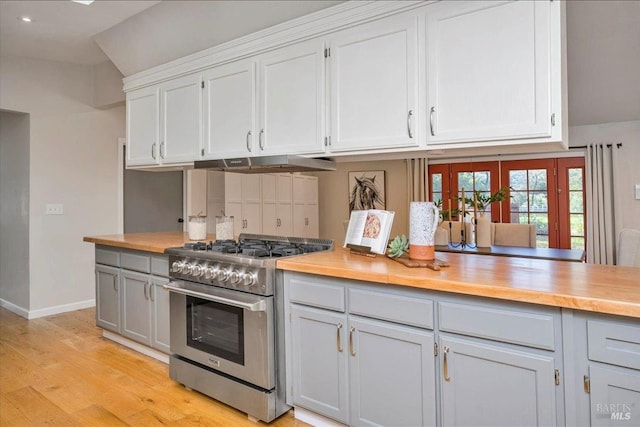 kitchen with extractor fan, light hardwood / wood-style flooring, high end stainless steel range, white cabinets, and lofted ceiling