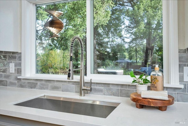 room details featuring decorative backsplash, sink, and light stone counters