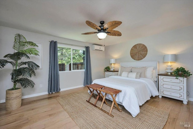 bedroom with a wall unit AC, ceiling fan, and light hardwood / wood-style flooring