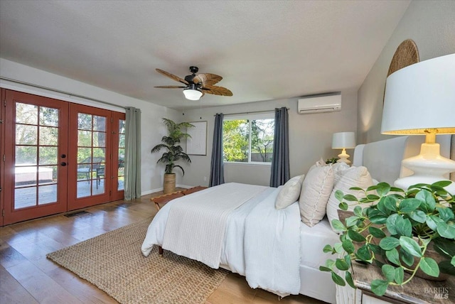 bedroom featuring french doors, access to outside, a wall mounted AC, ceiling fan, and wood-type flooring