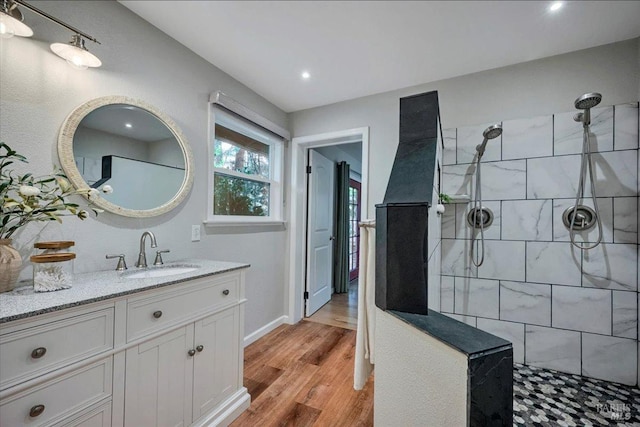 bathroom with wood-type flooring, vanity, and a tile shower