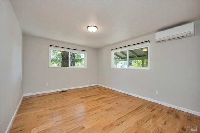 unfurnished room featuring a wall unit AC and light hardwood / wood-style flooring