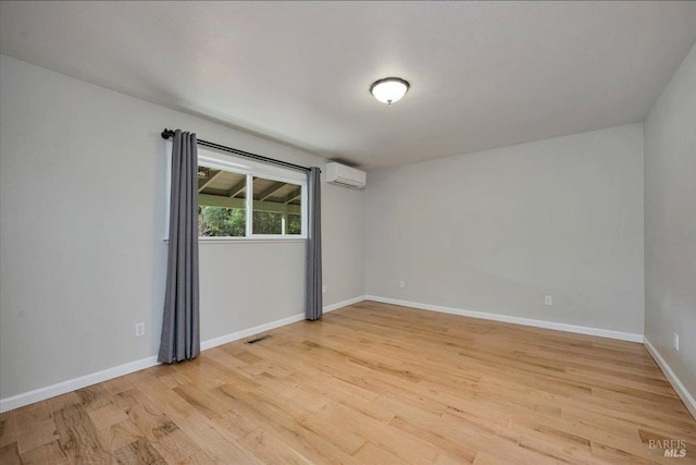 unfurnished room featuring a wall unit AC and light wood-type flooring