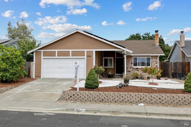ranch-style home featuring solar panels, brick siding, fence, concrete driveway, and an attached garage