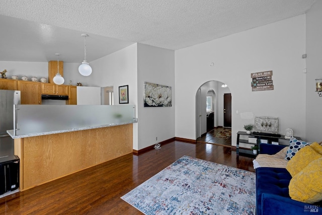 living area featuring baseboards, arched walkways, a textured ceiling, and wood finished floors