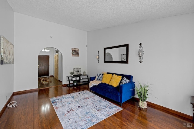 living area with arched walkways, baseboards, a textured ceiling, and hardwood / wood-style floors