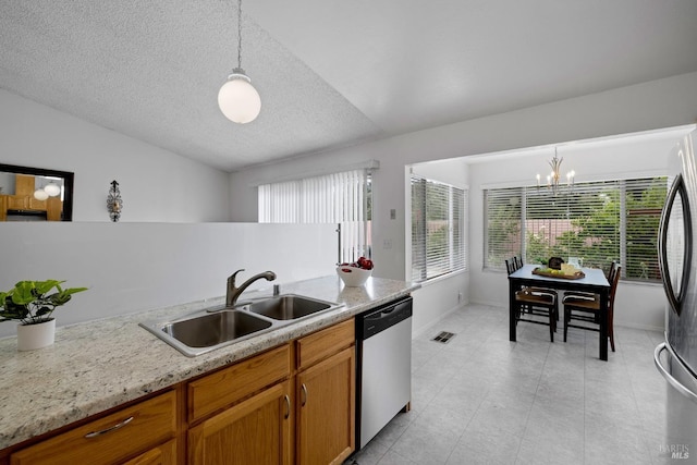 kitchen featuring a sink, appliances with stainless steel finishes, an inviting chandelier, and a wealth of natural light