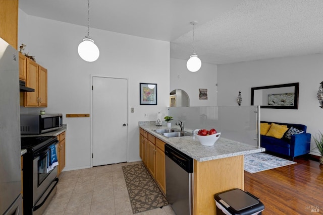 kitchen with a peninsula, light countertops, under cabinet range hood, a sink, and stainless steel appliances