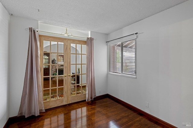 unfurnished room featuring a textured ceiling, baseboards, and wood finished floors